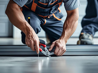 Technician performing detailed garage door maintenance in Aliso Viejo Close-up of a technician making adjustments to a garage door track, showing maintenance service in a clean, modern garage
