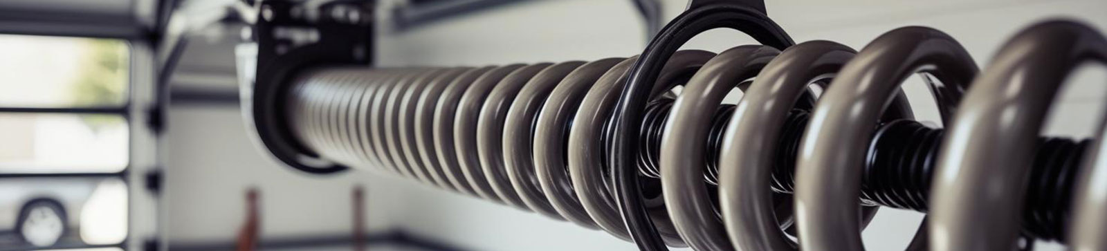 Large, durable garage door torsion spring positioned in a sunlit modern garage, symbolizing professional torsion spring replacement services