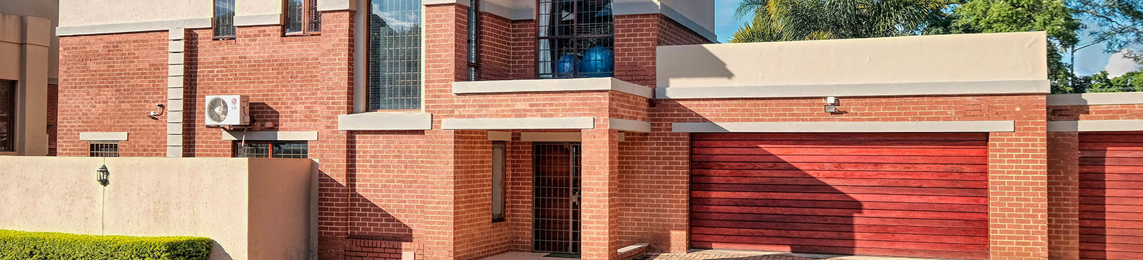 Two-car modern home with elegant red wood residential garage doors and brickwork, showcasing stylish options for homeowners